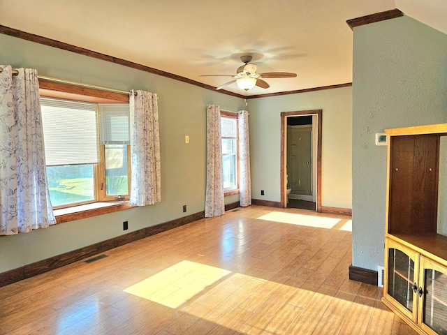 unfurnished room with crown molding, wood finished floors, baseboards, and ceiling fan