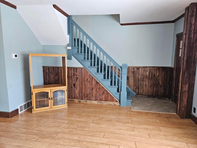 stairs featuring wood finished floors and ornamental molding
