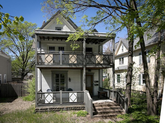 view of front of home with a balcony, covered porch, and fence