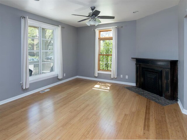 unfurnished living room featuring ceiling fan, wood finished floors, baseboards, and a fireplace with flush hearth