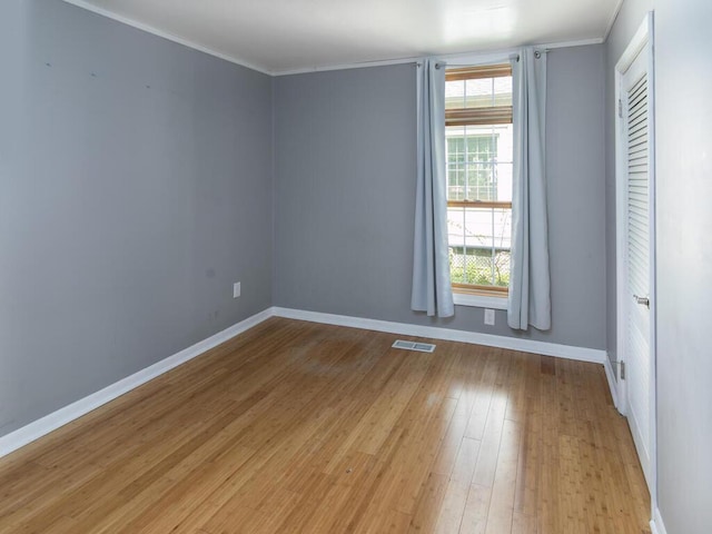 empty room with baseboards, light wood-type flooring, and crown molding