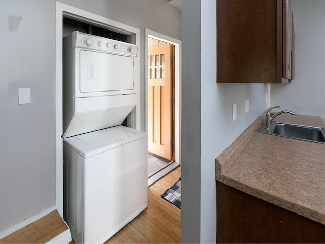 laundry area featuring estacked washer and dryer, light wood-type flooring, and baseboards