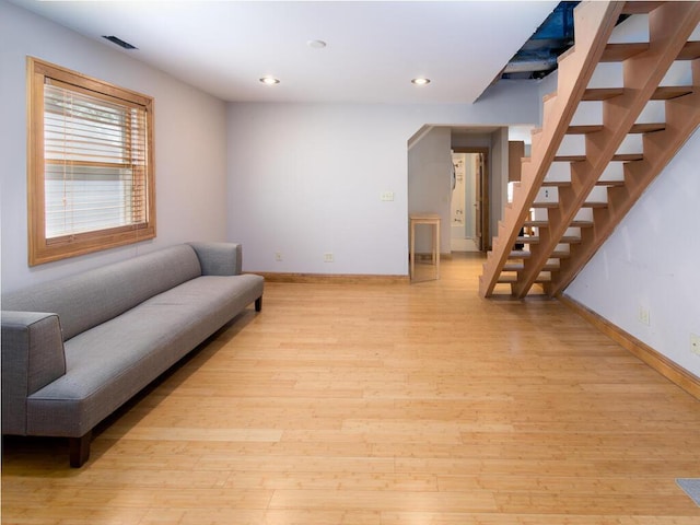 living area with baseboards, light wood finished floors, recessed lighting, and stairway