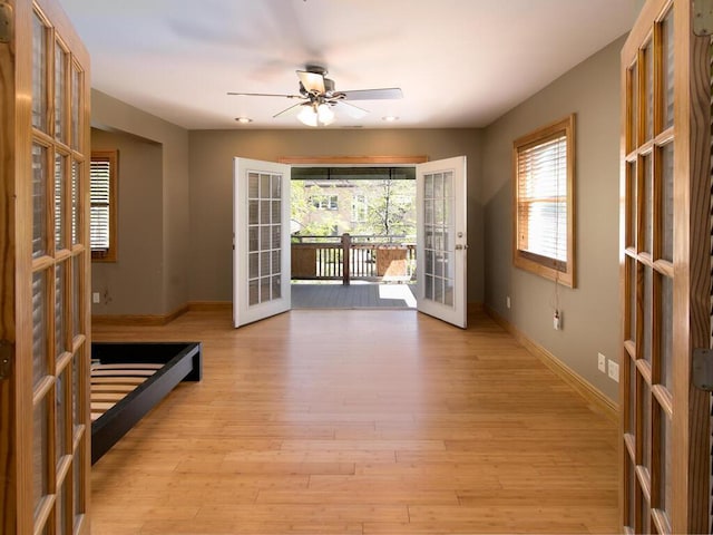 doorway featuring french doors, baseboards, a ceiling fan, and light wood-type flooring