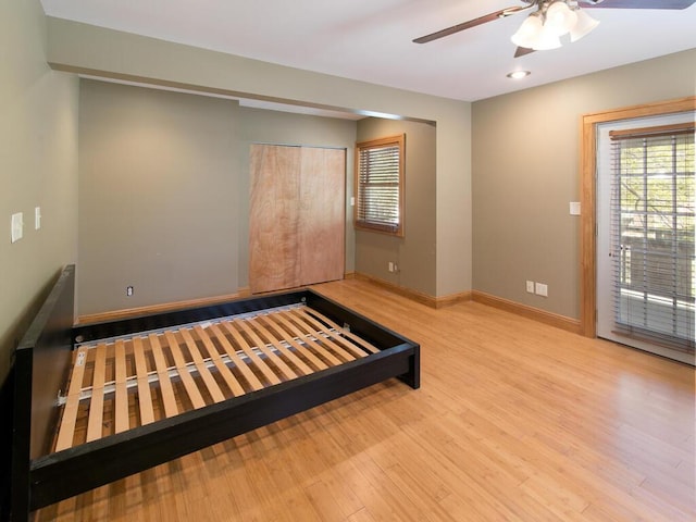 unfurnished bedroom featuring wood finished floors, baseboards, access to exterior, a closet, and ceiling fan