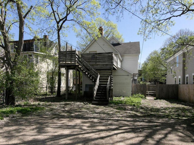 rear view of house featuring stairway and fence