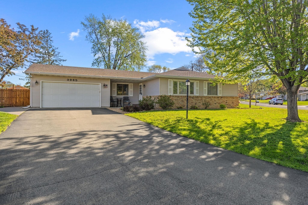 ranch-style house with an attached garage, asphalt driveway, and brick siding