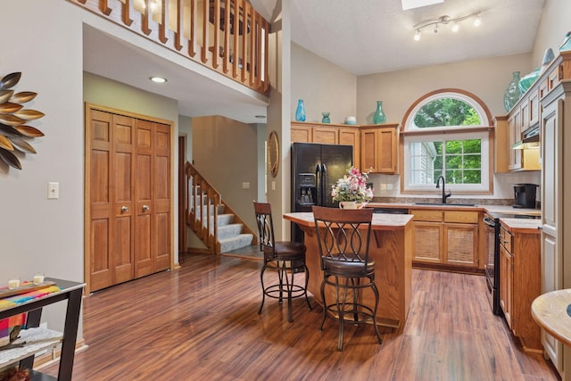 5662 Donegal Dr, Shoreview, MN 55126 - kitchen featuring a kitchen island, wood finished floors, range with electric cooktop, and black fridge with ice dispenser
