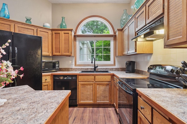 5662 Donegal Dr, Shoreview, MN 55126 - kitchen with black appliances, under cabinet range hood, light countertops, tasteful backsplash, and light wood-style floors