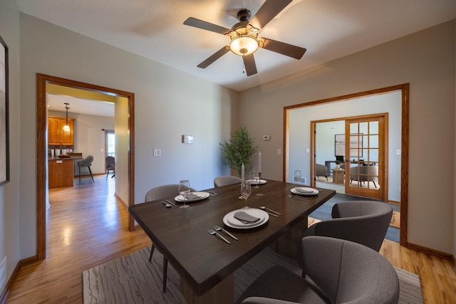 dining area featuring light wood finished floors, a ceiling fan, and baseboards