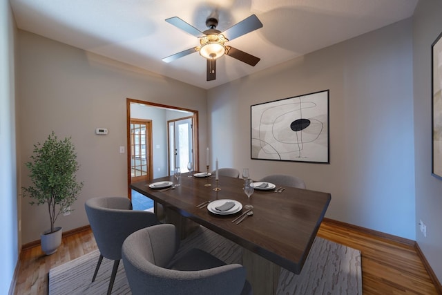 dining room with a ceiling fan, baseboards, and wood finished floors