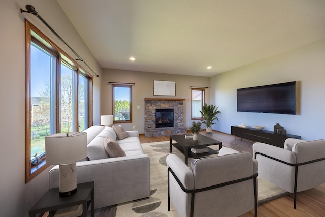 living area featuring light wood finished floors, a stone fireplace, and recessed lighting