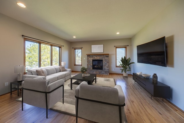 living area featuring wood finished floors, recessed lighting, and a stone fireplace