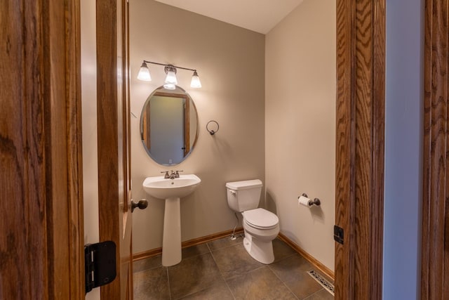 bathroom featuring toilet, baseboards, tile patterned flooring, and a sink