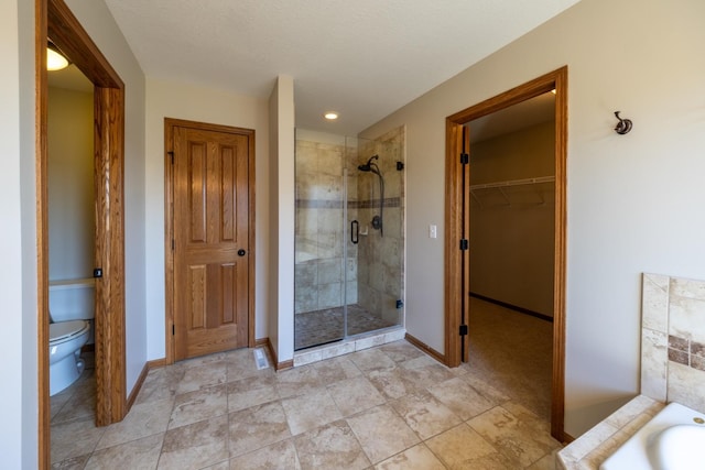 full bath with a stall shower, toilet, baseboards, a spacious closet, and recessed lighting