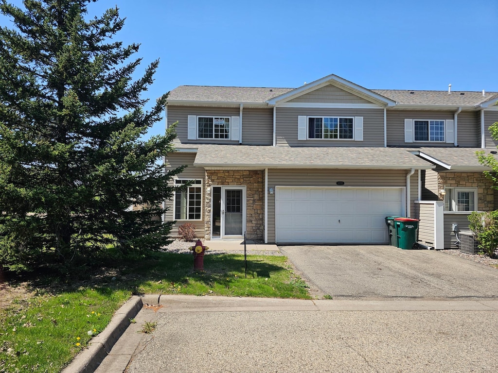 1870 Fisher Way Unit E, River Falls, WI 54022 - townhome / multi-family property featuring asphalt driveway, stone siding, a garage, and roof with shingles