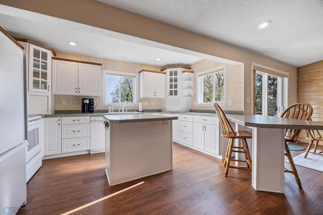 24295 Matson Point Trl, Lida Twp, MN 56572 - kitchen with white appliances, a kitchen breakfast bar, a textured ceiling, glass insert cabinets, and dark wood-style flooring
