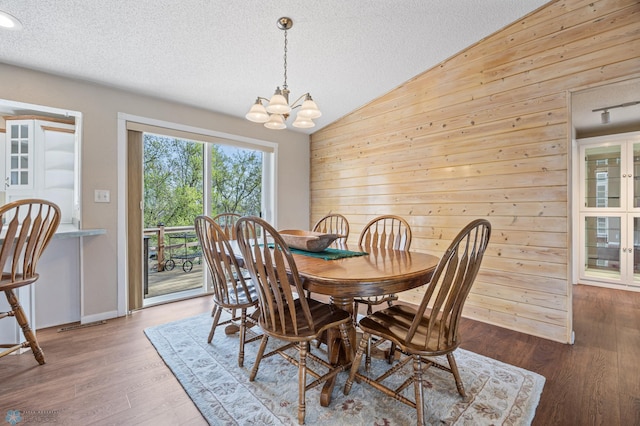24295 Matson Point Trl, Lida Twp, MN 56572 - dining space featuring vaulted ceiling, wooden walls, a chandelier, a textured ceiling, and wood finished floors