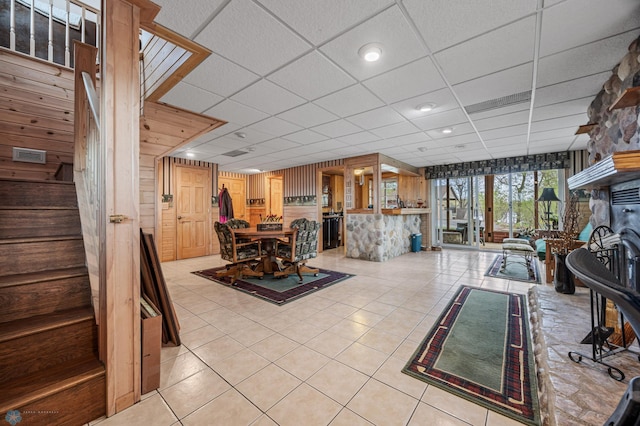 24295 Matson Point Trl, Lida Twp, MN 56572 - dining space with light tile patterned floors, a paneled ceiling, wood walls, and stairway