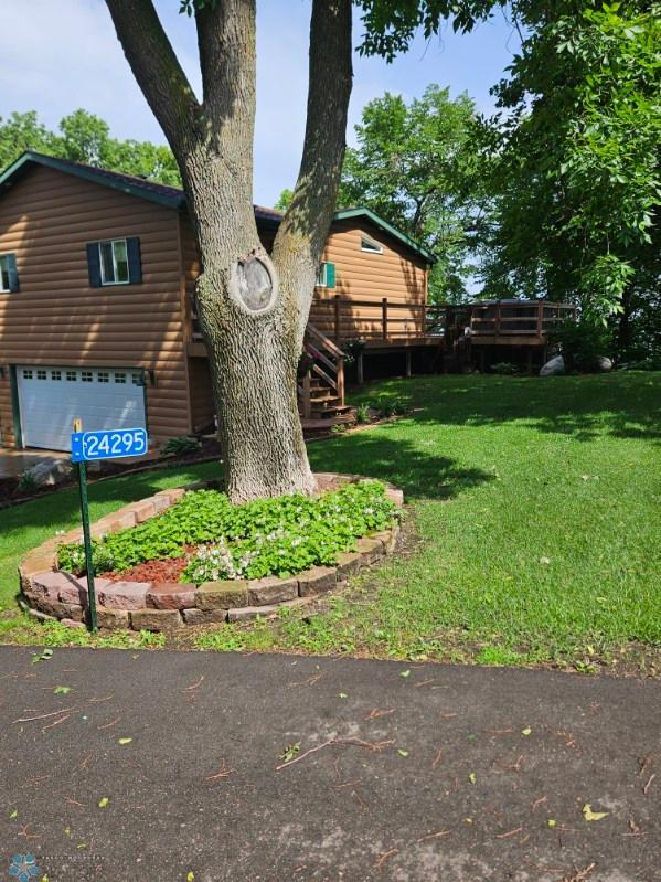 24295 Matson Point Trl, Lida Twp, MN 56572 - view of green lawn with a wooden deck, an attached garage, and stairs