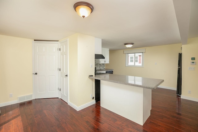 kitchen featuring under cabinet range hood, dark wood-style floors, baseboards, white cabinets, and a center island