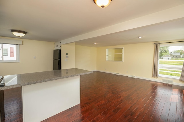 empty room featuring dark wood finished floors, healthy amount of natural light, and baseboards