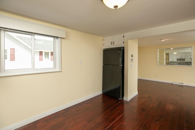 spare room with dark wood-style flooring and baseboards