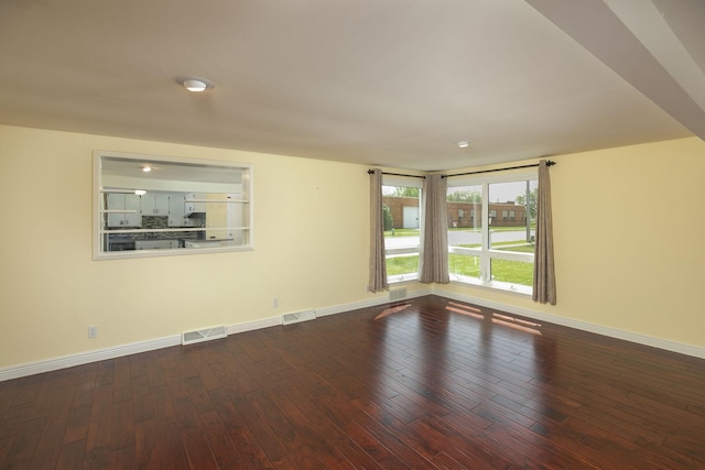 spare room with dark wood-type flooring and baseboards