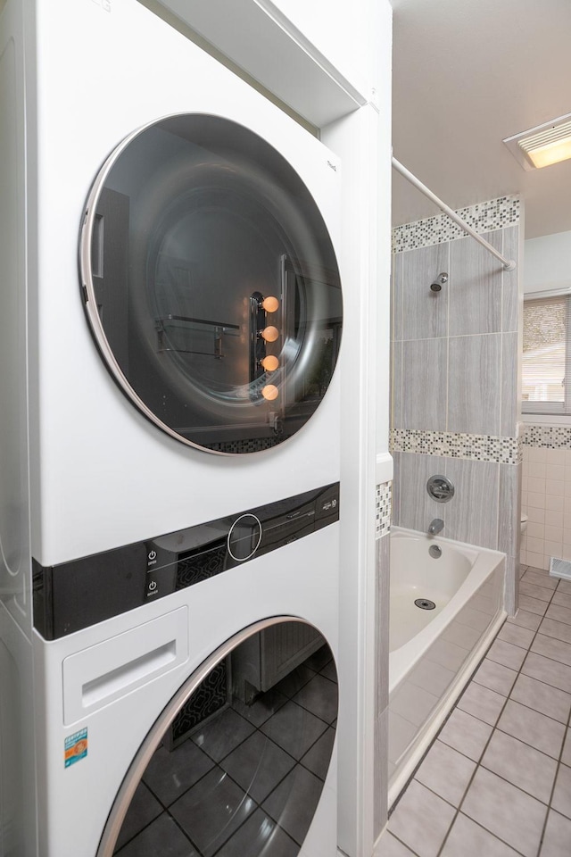 laundry room with stacked washing machine and dryer and tile patterned floors