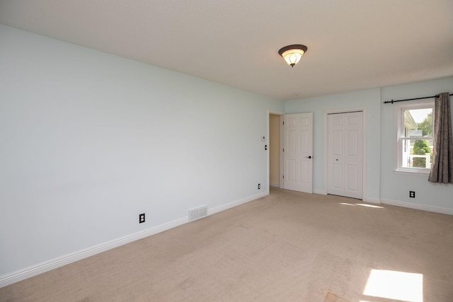 unfurnished bedroom featuring light colored carpet, baseboards, and a closet