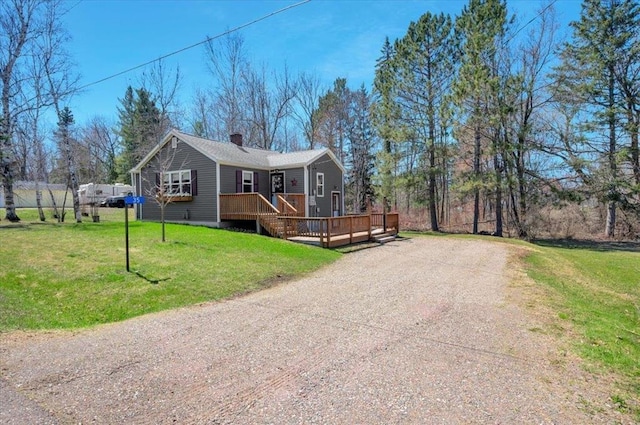 manufactured / mobile home featuring a deck, driveway, a chimney, and a front lawn