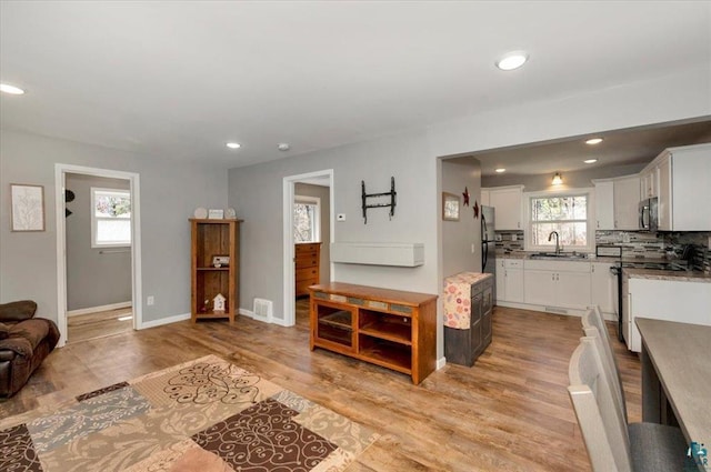 living room with light wood-type flooring, recessed lighting, and baseboards