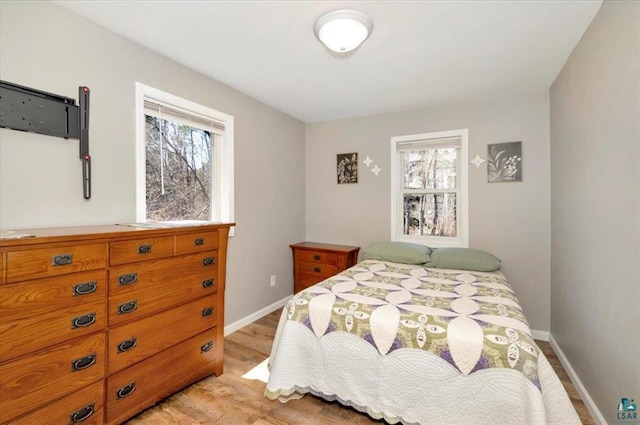 bedroom featuring multiple windows, light wood-type flooring, and baseboards