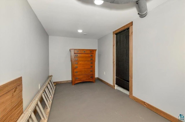 corridor with a heating unit, concrete flooring, and baseboards