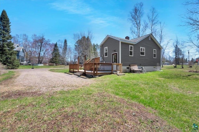 view of home's exterior with a deck, a lawn, and a chimney