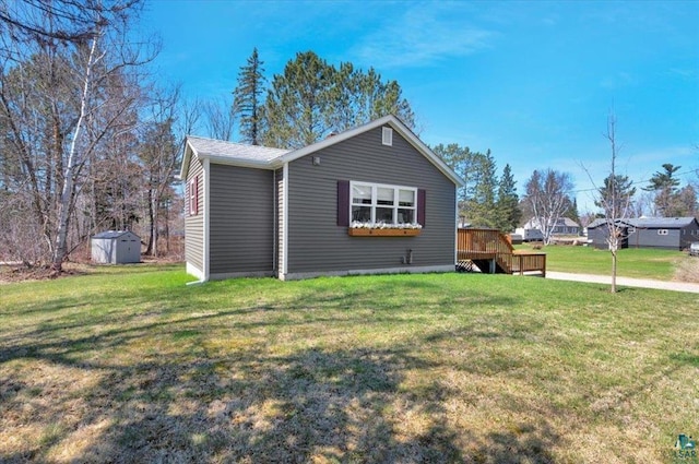 view of front of property with a storage unit, a wooden deck, an outbuilding, and a front yard