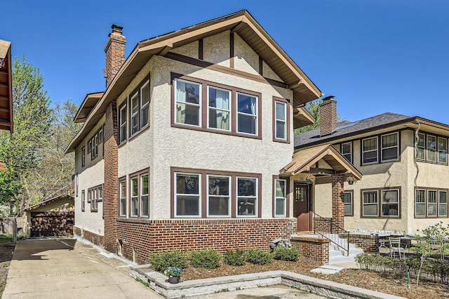 view of front of home featuring a chimney, stucco siding, and brick siding