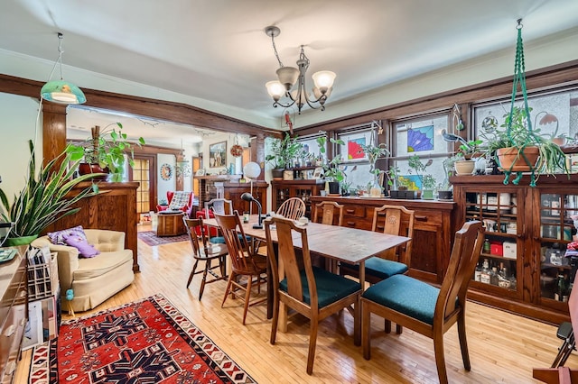 dining space featuring a chandelier, light wood finished floors, and crown molding