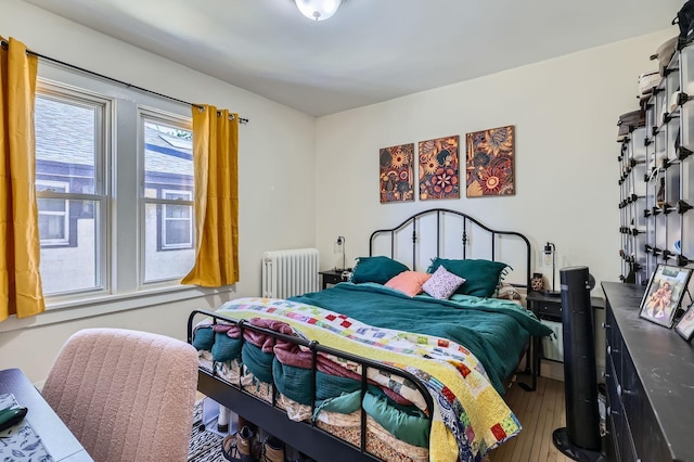 bedroom with radiator and hardwood / wood-style floors