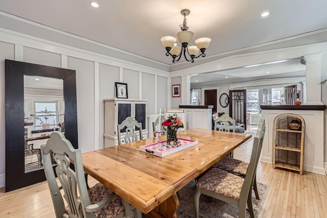 dining room with a decorative wall, ornate columns, ornamental molding, plenty of natural light, and a chandelier