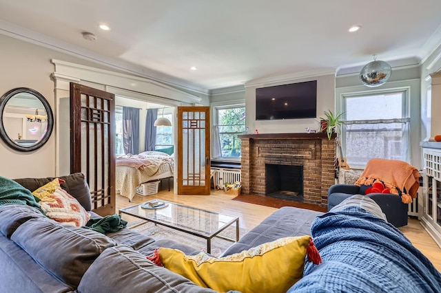 living room with ornamental molding, radiator, wood finished floors, a fireplace, and recessed lighting