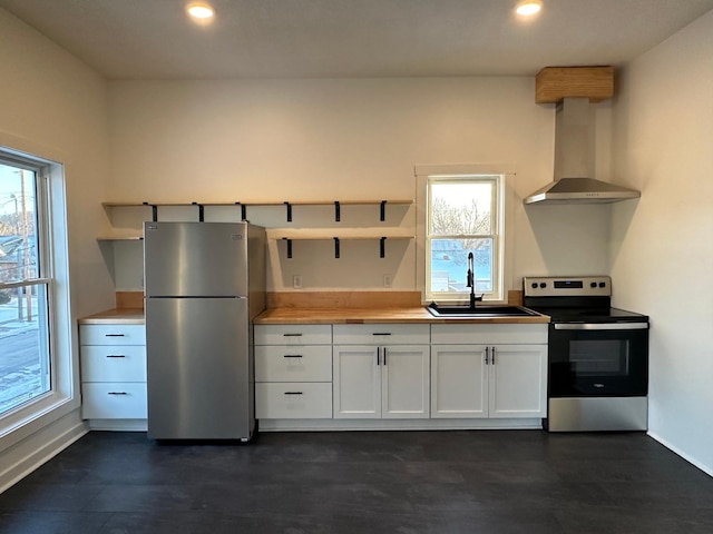 504 Buchanan St, Red Wing, MN 55066 - kitchen with appliances with stainless steel finishes, wall chimney exhaust hood, a sink, white cabinetry, and healthy amount of natural light