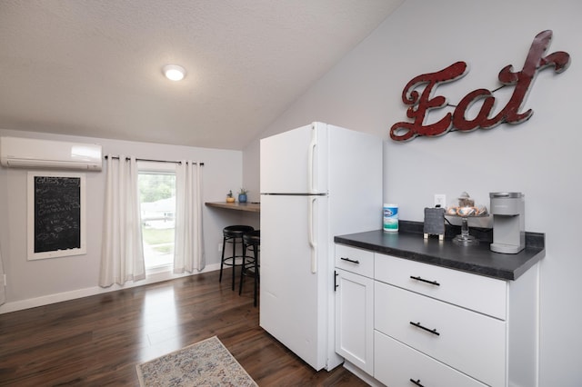 504 Buchanan St, Red Wing, MN 55066 - kitchen with a wall unit AC, freestanding refrigerator, vaulted ceiling, dark countertops, and dark wood-type flooring