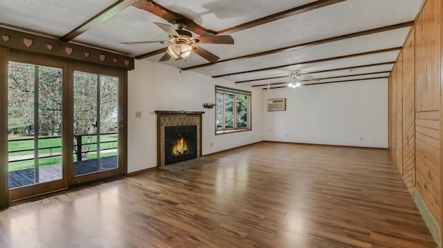 unfurnished living room with wood finished floors, beamed ceiling, ceiling fan, a brick fireplace, and baseboards