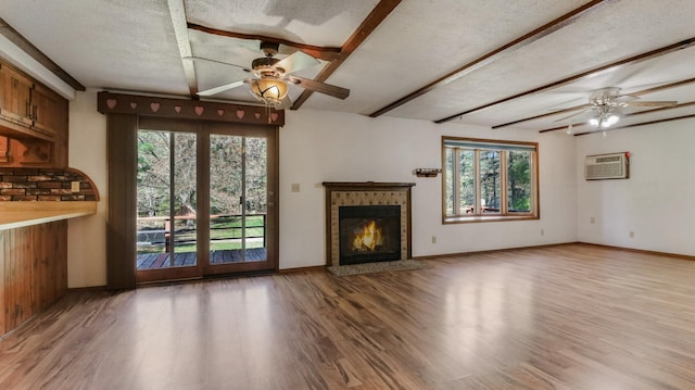 unfurnished living room featuring a ceiling fan, plenty of natural light, light wood-type flooring, beam ceiling, and a fireplace