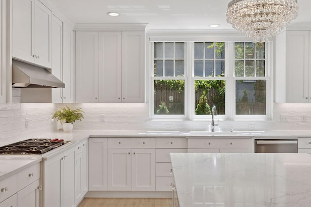 4201 Dupont Ave S, Minneapolis, MN 55409 - kitchen with under cabinet range hood, appliances with stainless steel finishes, a chandelier, a sink, and white cabinets