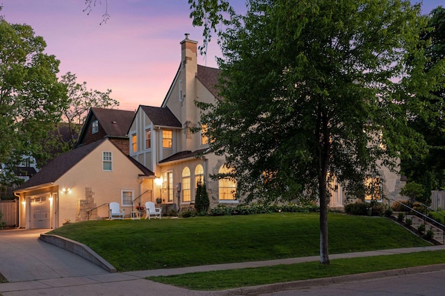 4201 Dupont Ave S, Minneapolis, MN 55409 - view of front of home with concrete driveway, a chimney, a front lawn, stucco siding, and an attached garage