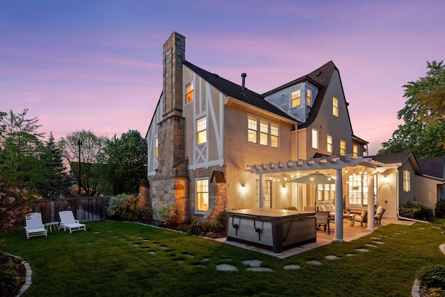 4201 Dupont Ave S, Minneapolis, MN 55409 - back of property at dusk with a hot tub, a pergola, stone siding, stucco siding, and a patio