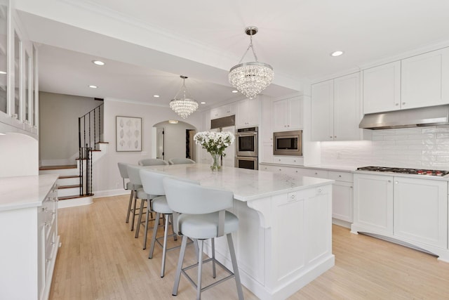 4201 Dupont Ave S, Minneapolis, MN 55409 - kitchen with stainless steel appliances, under cabinet range hood, arched walkways, white cabinetry, and recessed lighting