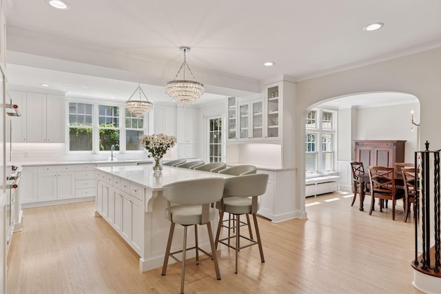 4201 Dupont Ave S, Minneapolis, MN 55409 - kitchen with arched walkways, radiator, a center island, white cabinetry, and light wood-style floors